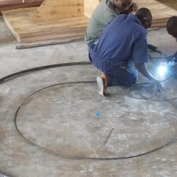 Educators master the pivotal processes of bending and welding to construct the parabolic skeleton of industrial solar cookers.